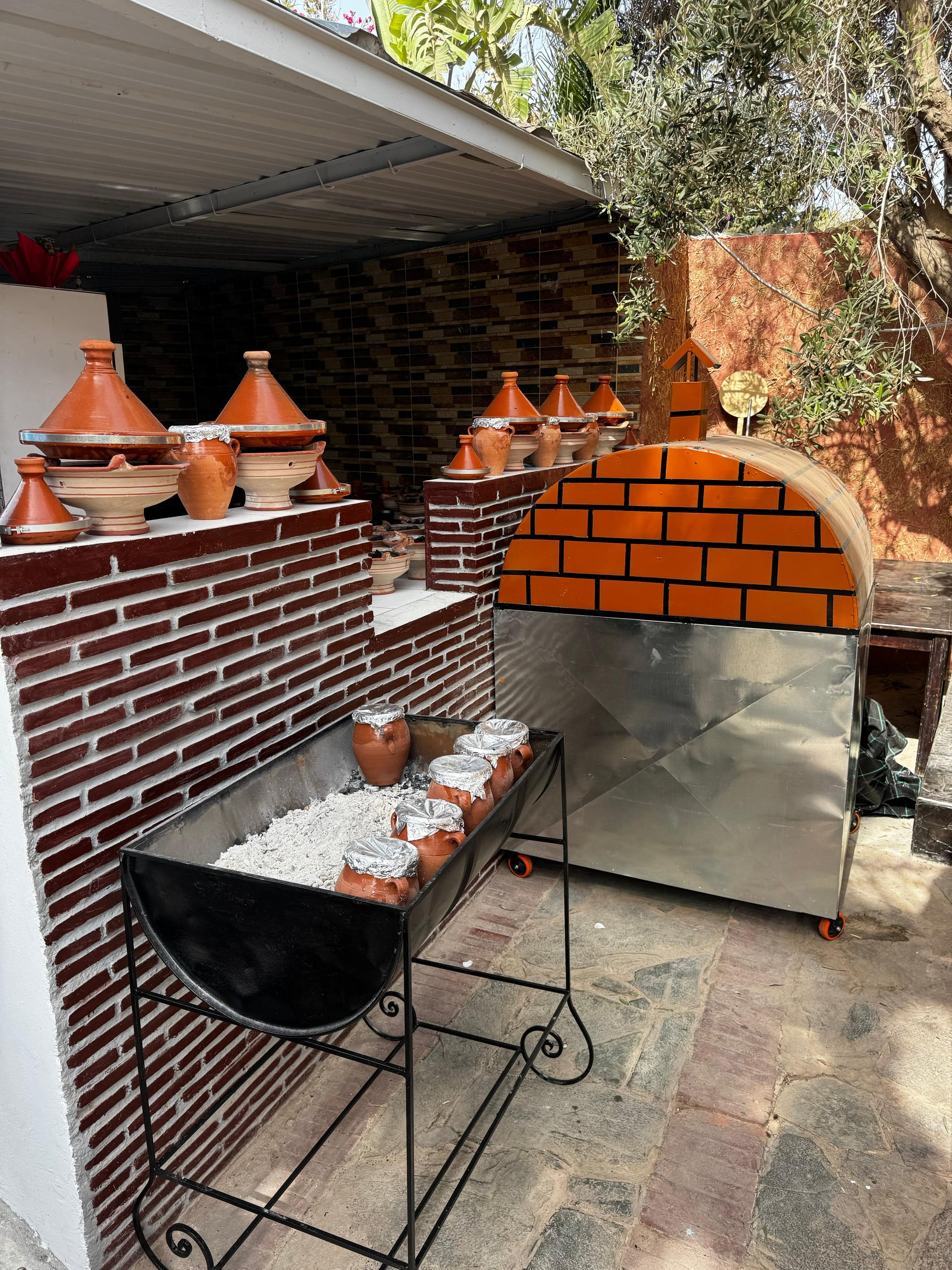Traditional Moroccan claypot tagine cooking station over hot charcoal embers at Restaurant Bab Aourir